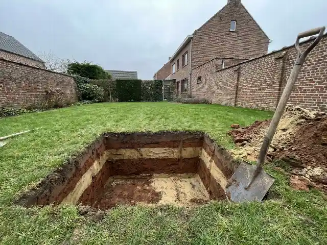 Proefput in een Vlaamse tuin met zichtbare lagen zand en klei