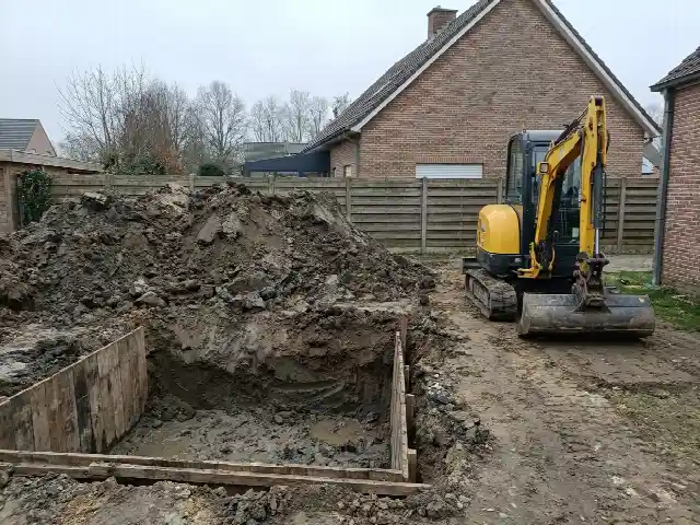 Uitgegraven grond naast de put voor een nieuw zwembad